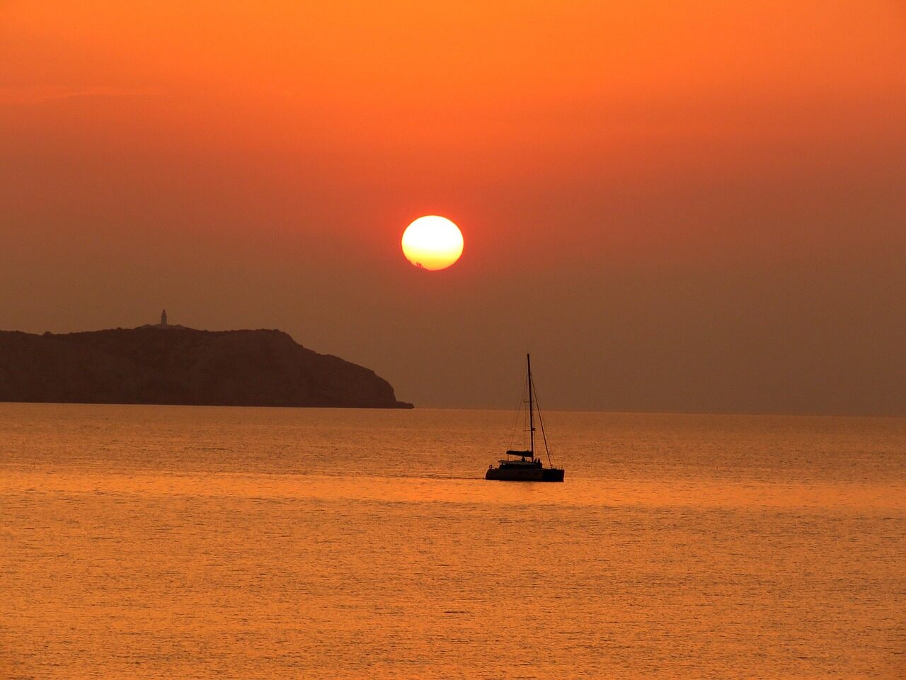 Sonnenuntergang über dem Meer vor Ibiza mit Segelboot in Silhouette